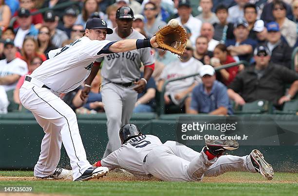 Nick Punto of the Boston Red Sox slides into first on a bunt single as Justin Smoak of the Seattle Mariners takes the throw at Safeco Field on July...
