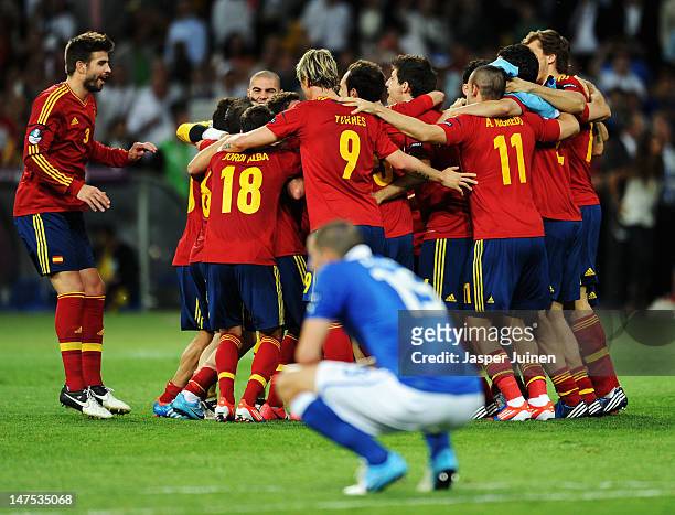 Spain players celebrate victory as Andrea Barzagli of Italy shows his dejection after the UEFA EURO 2012 final match between Spain and Italy at the...