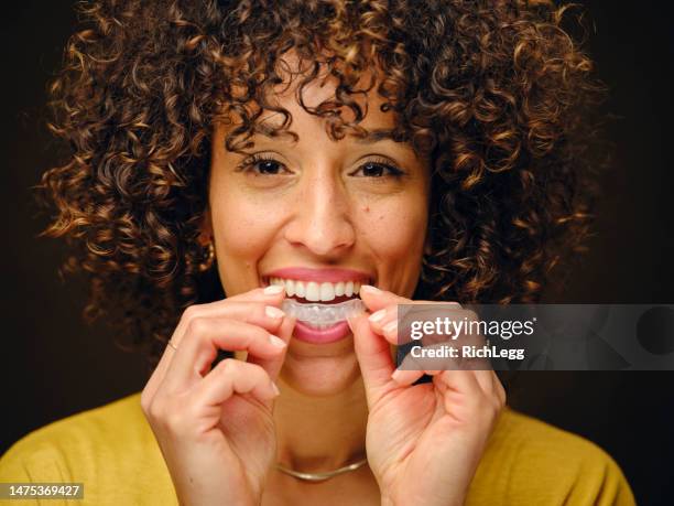 happy young woman holding inivisible teeth aligners - brace 個照片及圖片檔