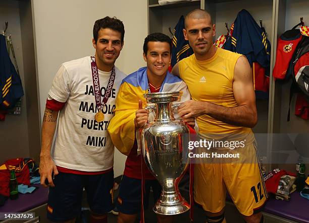 Cesc Fabregas, Pedro and Victor Valdes of Spain pose with the trophy in the dressing room following the UEFA EURO 2012 final match between Spain and...