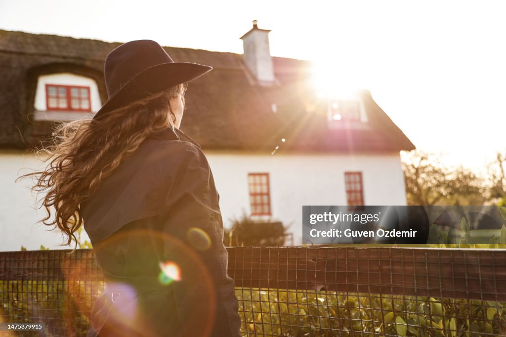 Village house in old Irish traditions, Thatched cottage and young girl, Irish girl and Irish village house, traditional English house, back view of girl holding garden fence, thatched cottage Irish Village, british village house, irish village house