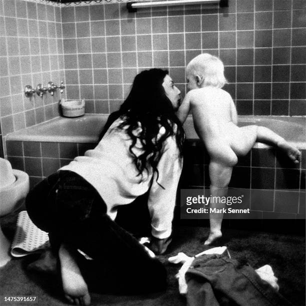Musician Cher in a candid portrait with her son Elijah Blue who is climbing into a bathtub at Cher's house circa 1978 in Los Angeles, California