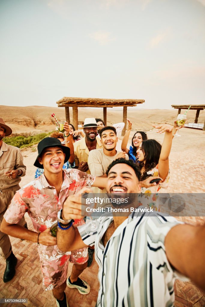 Medium shot friends on vacation taking selfie at luxury desert camp