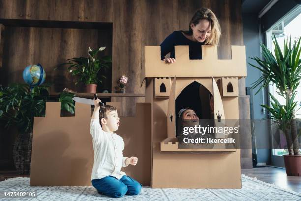 mother and children playing role play game at home with castle made of cardboard - casa de brinquedo imagens e fotografias de stock