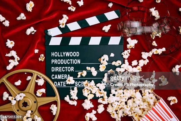 clapperboard, film reel, film and spilled popcorn on red satin background. - cinematografi bildbanksfoton och bilder