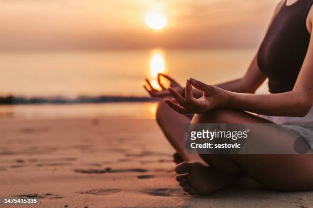woman meditating on the beach at sunset - zen sand stock pictures, royalty-free photos & images