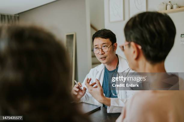 personal doctor giving an advice while consulting with senior adult patient. - southeast asian ethnicity stock pictures, royalty-free photos & images