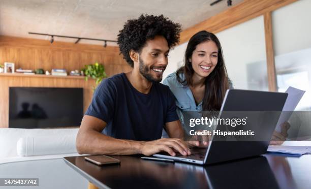young couple paying bills online using a laptop - conta acessório financeiro imagens e fotografias de stock