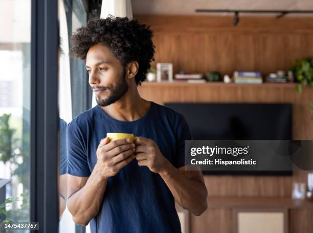 nachdenklicher mann, der zu hause eine tasse kaffee trinkt - natural hair stock-fotos und bilder