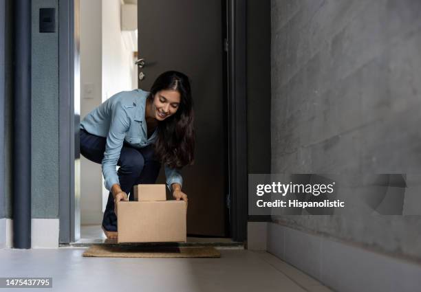 mujer feliz en casa recibiendo algunos paquetes por correo - recibir fotografías e imágenes de stock