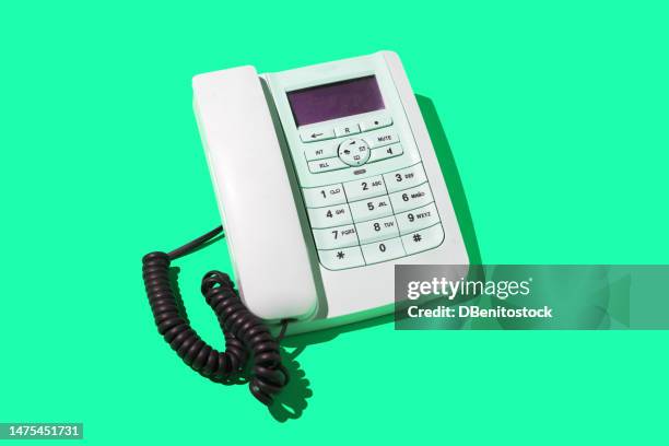 white retro telephones, with cord, on a turquoise green background. concept of old, telephony, landline, talk, distance, listen, switchboard and customer service. - telefone fixo imagens e fotografias de stock