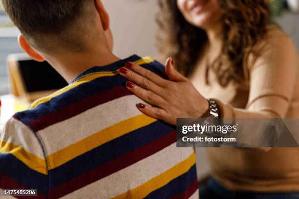 mother holding hand on her son's shoulder while studying - hand on shoulder stock pictures, royalty-free photos & images