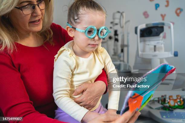 oftalmóloga sénior, trabajando con una paciente pequeña en la clínica de oftalmología - miopía fotografías e imágenes de stock