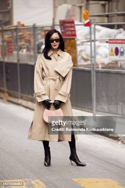 Chriselle Lim wears a beige trench coat, black leather gloves, dusty pink bag and black boots outside Lanvin Paris Fashion Week - Womenswear Fall...