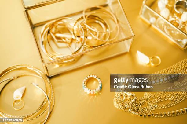 gold and gem jewelry on golden surface. - gold hoop earring stockfoto's en -beelden
