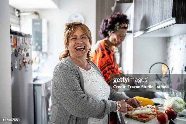 portrait of a mature woman cutting vegetables in the kitchen at home - woman chores stock pictures, royalty-free photos & images