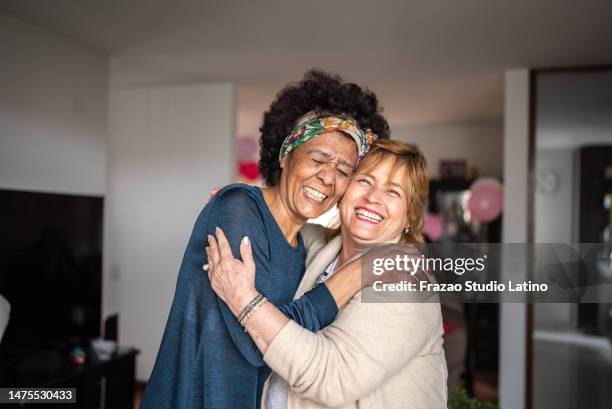 portrait of senior friends embracing at home - neighbor stock pictures, royalty-free photos & images