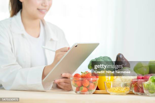 we specialized in weight loss plans to improving your eating habits. nutritionists use a tablet computer to do weight loss plans for their customers via a mobile application. - nutricionista imagens e fotografias de stock