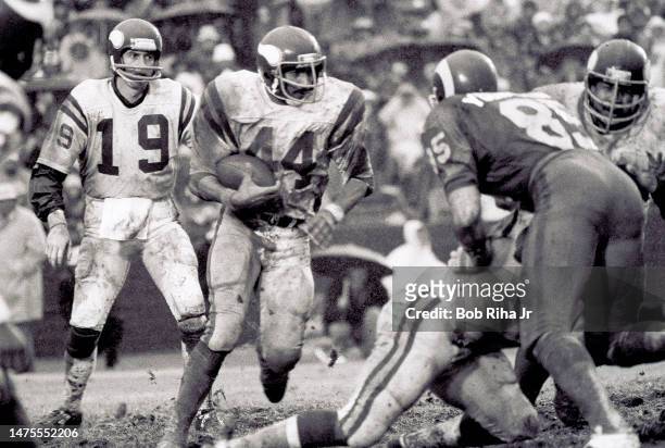 Vikings RB Chuck Foreman breaks free on run play after getting ball from QB Bob Lee as Rams Jack Youngblood blocks route during rainstorm at NFC...