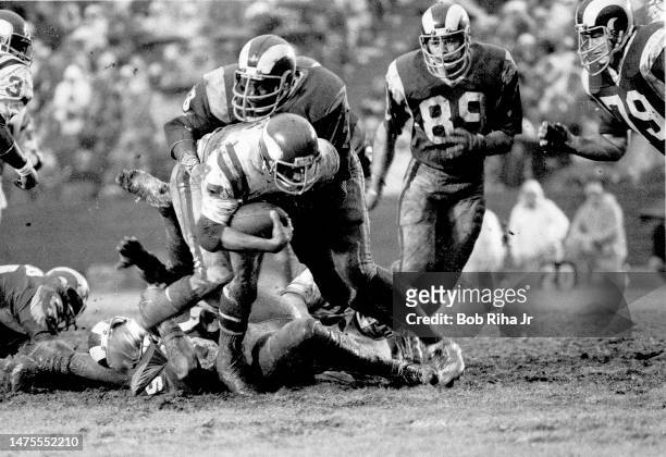 Vikings RB Chuck Foreman gets tackled by Rams Cody Jones as Fred Dryer and Mike Fanning close-in during rainstorm at NFC Playoff Game between Los...