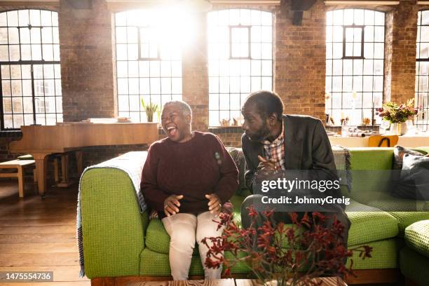 senior black couple talking and laughing in loft apartment - annual companions stock pictures, royalty-free photos & images