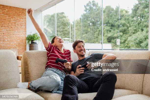 pareja jugando videojuegos juntos - videojuego fotografías e imágenes de stock