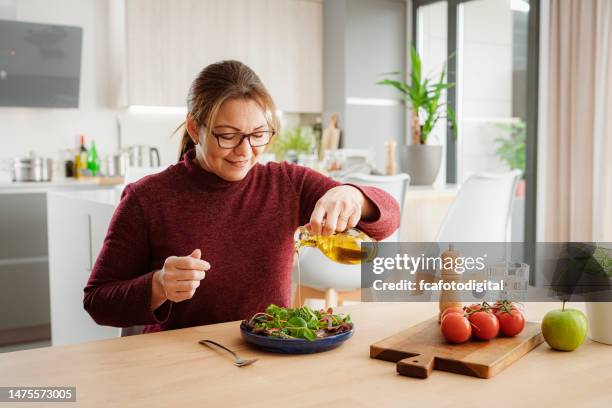 cheerful mature woman dressing on salad - mediterranean diet stock pictures, royalty-free photos & images