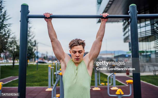 sporty man exercising in a recreational park - chin ups stockfoto's en -beelden