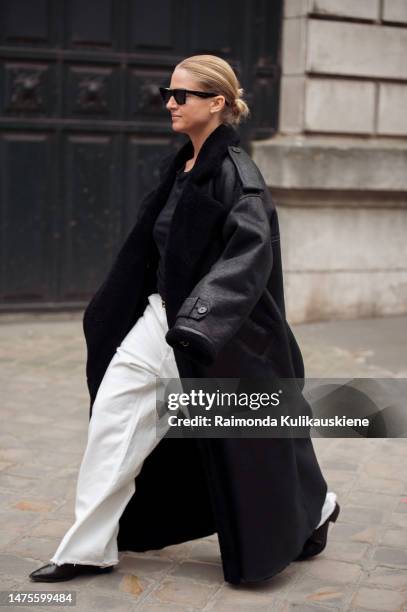 Guest is seen wearing a black top, white pants, and a black leather coat, outside the Hermes show during Paris Fashion Week - Womenswear Fall Winter...