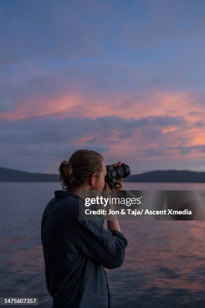 photographer takes photo of sunsetting over sea - auftauchen wasser stock-fotos und bilder