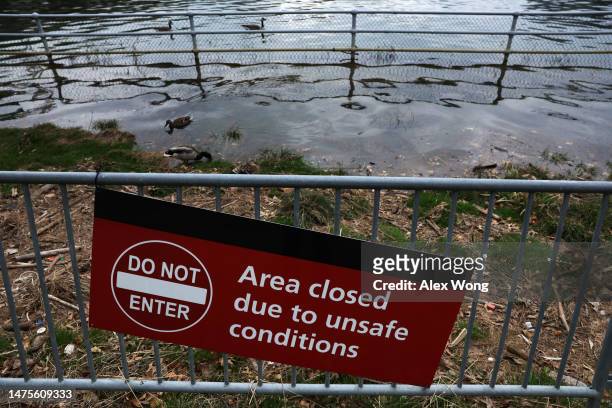 Do Not Enter" sign is on display as floodwaters wash up the bank during high tide across the Washington Channel from The Wharf amid cherry blossoms...