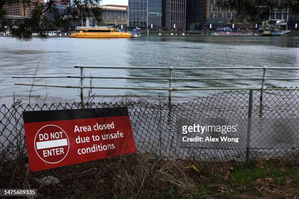 Do Not Enter" sign is on display as floodwaters wash up the bank during high tide across the Washington Channel from The Wharf amid cherry blossoms...
