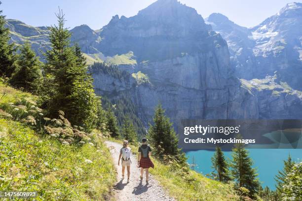 deux personnes randonnant dans un magnifique paysage alpin en été marchant dans les alpes suisses en profitant de la nature et du plein air - lac-oeschinensee photos et images de collection