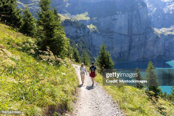 deux personnes randonnant dans un magnifique paysage alpin en été marchant dans les alpes suisses en profitant de la nature et du plein air - swiss alps photos et images de collection