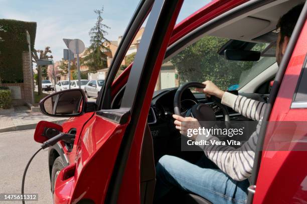 close-up view of unrecognizable man at electric car driving seat charging with solar energy - sustainable biodiesel alliance stock pictures, royalty-free photos & images