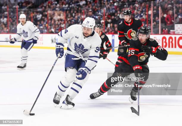 Auston Matthews of the Toronto Maple Leafs skates with the puck against Jake Sanderson of the Ottawa Senators during the first period at Canadian...