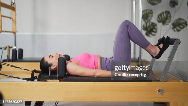 female pilates trainer working out on pilates machine in pilates studio - reformer stock pictures, royalty-free photos & images
