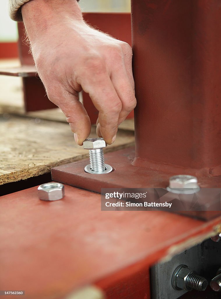 Worker inserting a bolt into a steel beam