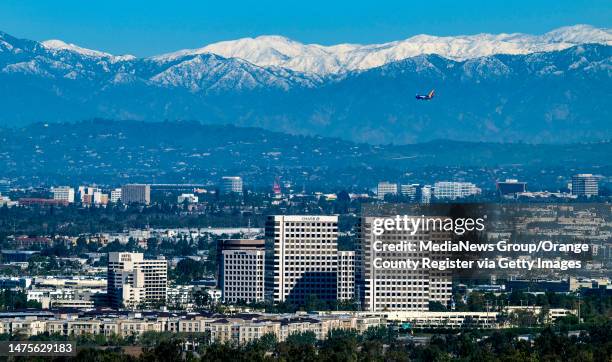 Orange, CA With the snow-covered San Gabriel Mountains in the background, a passenger jet makes a final approach to John Wayne Airport in this view...