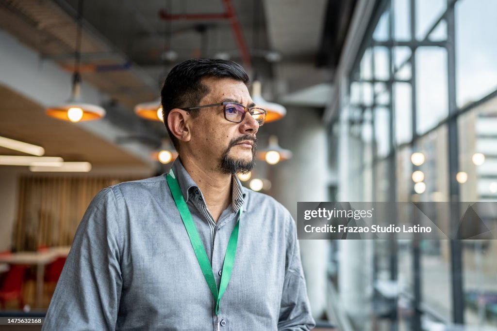 Mature man looking away contemplating at office
