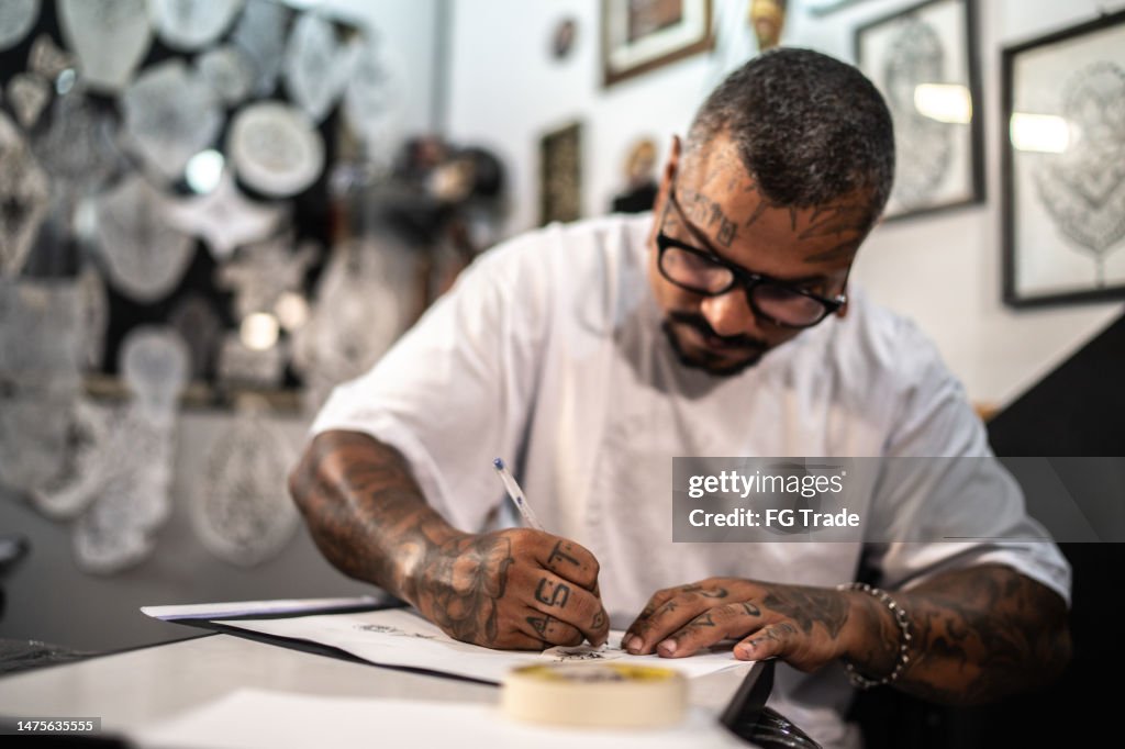 Tattoo artist drawing a tattoo on the paper at a tattoo studio