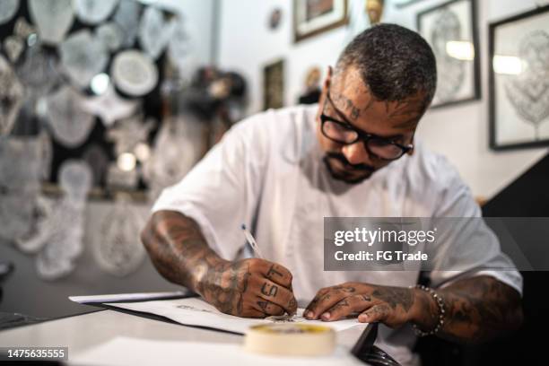 tattoo artist drawing a tattoo on the paper at a tattoo studio - kunst en nijverheid stockfoto's en -beelden