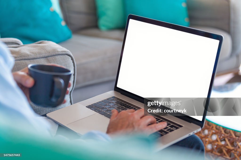 Reifer Mann, der zu Hause einen leeren Laptop benutzt.