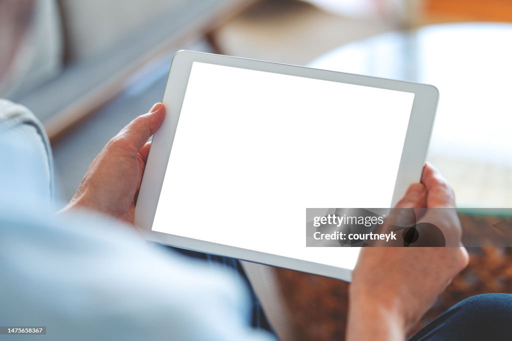 Reifer Mann, der zu Hause ein digitales Tablet mit leerem Bildschirm verwendet.