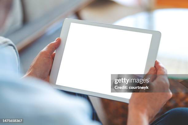 hombre maduro usando una tableta digital de pantalla en blanco en casa. - ipad fotografías e imágenes de stock