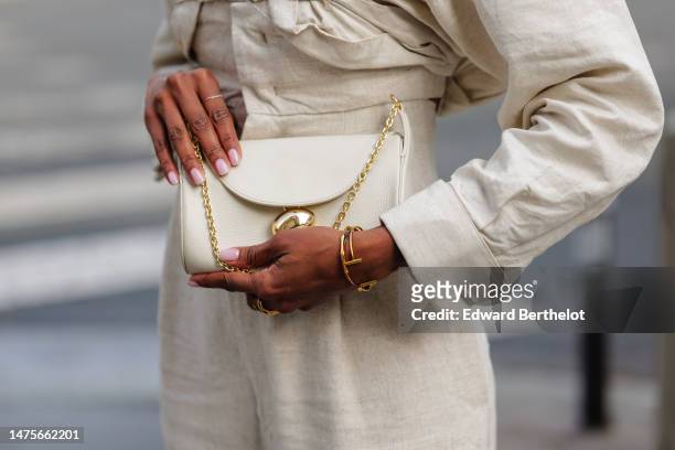 Emilie Joseph wears a white linen jumpsuit / corset "L'Année 97" by Jacquemus, a white bag from Cafune, golden bracelet, jewelry, during a street...