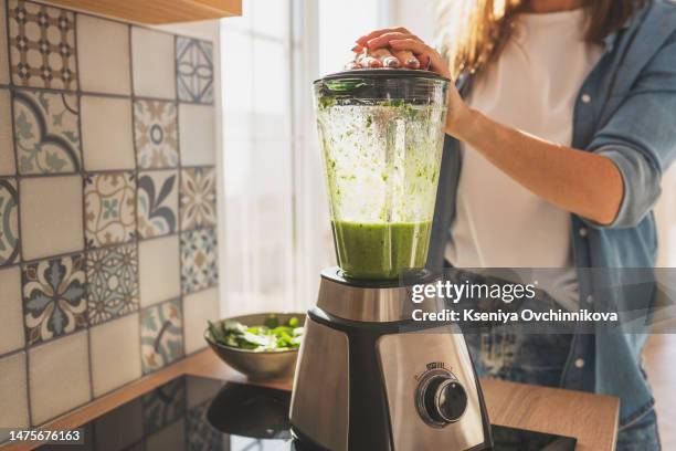 woman blending spinach, berries, bananas and almond milk to make a healthy green smoothie - blender foto e immagini stock