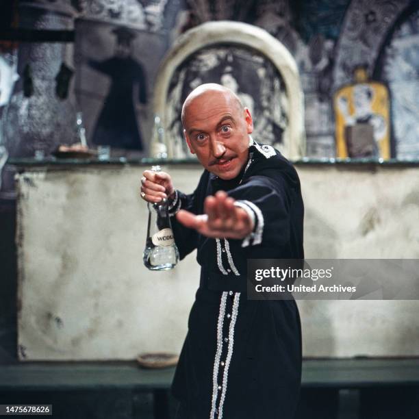 Karl Lieffen, deutscher Bühnen-, Fernseh- und Filmschauspieler, im Bühnenkostüm als Russe mit einer Flasche Wodka, Deutschland um 1979.