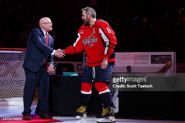 Alex Ovechkin of the Washington Capitals shakes hands with NHL Deputy Commissioner Bill Daly while being honored during a pre-game ceremony for...