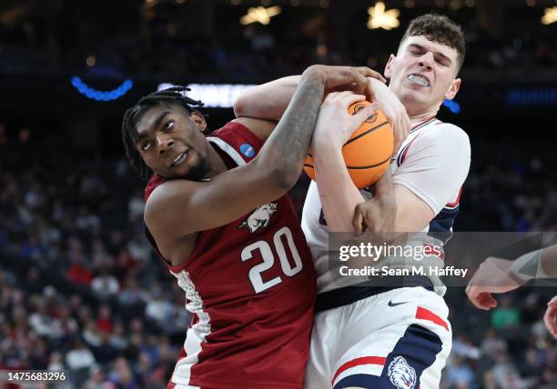 Donovan Clingan of the Connecticut Huskies battles Kamani Johnson of the Arkansas Razorbacks for the ball during the second half in the Sweet 16...